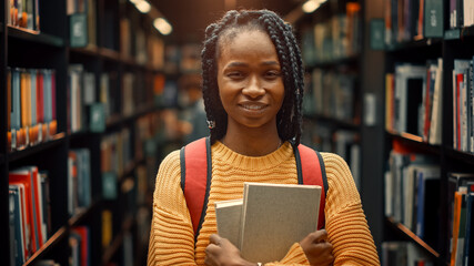 University Library Study: Portrait of a Smart Beautiful Black Girl Holding Study Text Books Smiling Looking at the Camera. Authentic Student Does Research for Class Assignment, Exams Preparationtion - Powered by Adobe