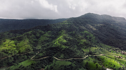 Fototapeta na wymiar Aerial/Drone View of a wide river shore with rural roads covered in green grass during Monsoon season in Maharashtra, India.