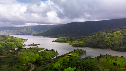Fototapeta na wymiar Aerial/Drone View of a river valley and an offbeat holiday resort in green surroundings during Monsoon season in Maharashtra, India.