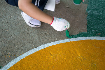 Volunteer painting stadium floor by hand.