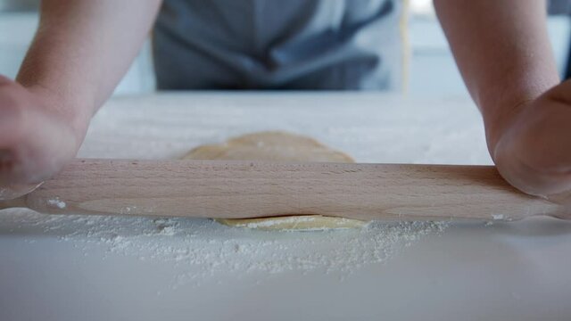 Close up Follow Focus, Anonymous person using a rolling pin to Roll out Dough at Home. Making Pasta.