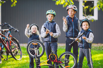 Children mechanics, bicycle repair. Happy kids fixing bike together outdoors in sunny day. Bicycle repair concept. Teamwork family posing with tools for repairing a bicycle in hands outside