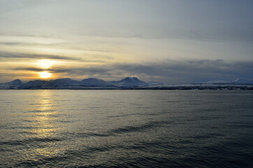 Fototapeta na wymiar beautiful sunset over snowy mountain and fjord