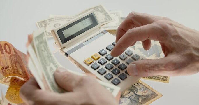 Counting money using old calculator, handeling international paper currency, pushing buttons. Counted summ on calculators screen. Money signs. Counting money. Home finances concept.