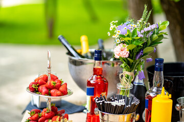 Fototapeta na wymiar catering. outdoor table with strawberries, beverages, flowers. buffet.
