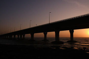 Fototapeta premium An evening by the beach: Bandra Worli Sea Link, Mumbai during Sunset, Silhouette of the bridge with Sun setting down