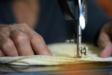 Selective focus on hands of mother old woman create pattern design and the old sewing machine for vintage design