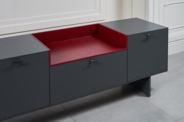Details modern minimalist TV stand graphite color with a decorative red insert made of natural wood on a white background