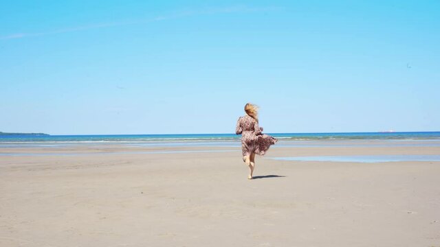 Beautiful young girl running towards the sean on the beach on a sunny day. Freedom concept