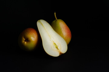Two pears and half on black background