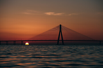 Fototapeta na wymiar An evening by the beach: Bandra Worli Sea Link, Mumbai View during Sunset, Silhouette of the bridge with Sun going down