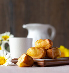 Small sponge biscuits, traditional French madeleines cakes, white and yellow wildflowers on the table. Breakfast or tea time concept