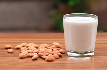 Almond milk with almond on a wooden table, Nature background and daylight, Selective focus, Health food with good fats and helps slow down aging, Antioxidants and helps to lower cholesterol levels.