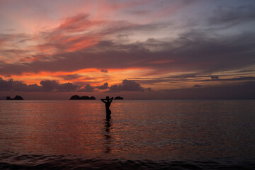 Silhouette of a woman in the water of sea or ocean at sunset.