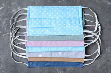 Homemade protective masks on grey stone background, flat lay. Sewing idea