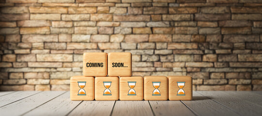 cubes with message COMING SOON in front of a brick wall