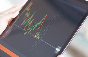 Fototapeta premium Closeup hand holding digital tablet computer with graph of Binary option for trading platform, setective focus