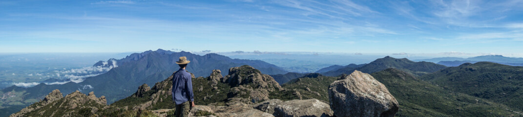 Hiker admiring Serra Fina mountain chain, after ascending to Couto Stone - Itatiaia State Park, Brazil