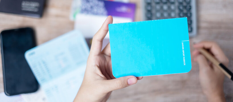 Woman Holding Savings Deposit Passbook And Using Calculator At Home Office Tax And Retirement Planning Concepts