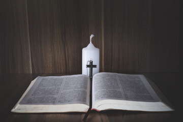 The crucifix lay on the bible. While there are candles that are illuminating Christian religious...