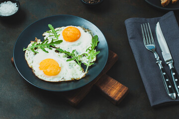 Fried egg. Fried egg with herbs on black plate on black background
