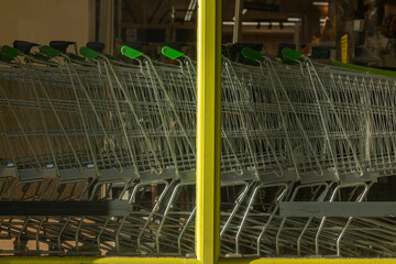 A group of metal shopping trolleys, made in Spain, stacked in the access area to a supermarket in Madrid, Spain.