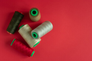 Bobbins on red background. Sew and tailoring concept, sewing tools, needlework.