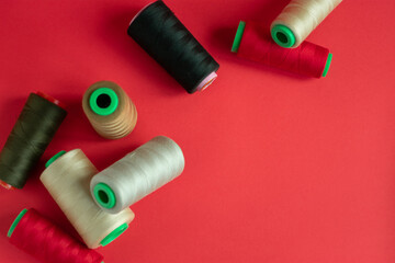 Bobbins on red background. Sew and tailoring concept, sewing tools, needlework.