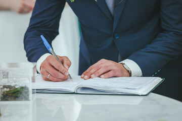 Businessman sitting at office desk signing a contract with shallow focus on signature.