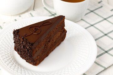 Piece of chocolate cake on white plate on table