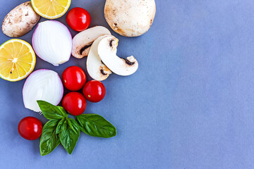 Vegetables on gray background. Mushrooms, cherry tomatoes, onion, basil, lemon for heathy food concept.