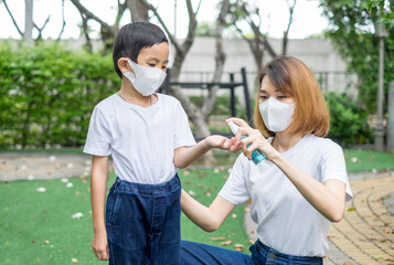 Asian mother using spray alcohol to her son for clean hands. Healthy family concept