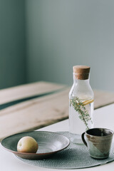 Infused fresh water with lemon and thyme in a glass decanter on the table in the interior of the room in the Scandinavian style. 