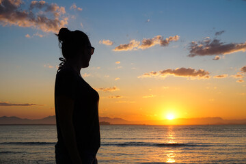 Silhouette of a woman contemplating a beautiful sunset in Ilha do Mel, Paraná, Brazil