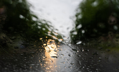 Raindrops on a windscreen glass with a blurred night city lights at the background.