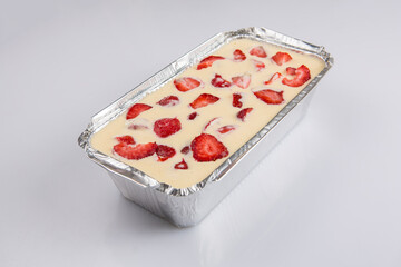 isolated close corner view of a Russian zapekanka strawberry pudding cottage ice cream cheese cake in a foil baking pan on a white background