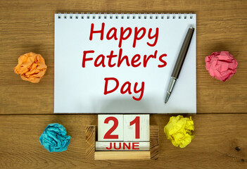 White note with inscription 'Happy Father's Day' on beautiful wooden table, colored paper, metalic pen and wooden calender with date 21 june. Concept.