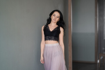 Fototapeta premium beautiful girl in a black top and pink skirt enters the room