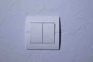 Plastic mechanical white light switch, installed on a light gray wall. High quality photo