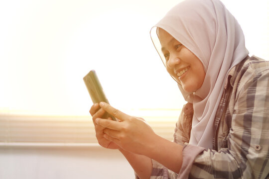 Closeup of Asian muslim woman using a smart phone. Happy smiling gesture having good news when communicating on internet , video call