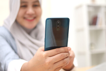 Closeup of Asian muslim woman using a smart phone. Happy smiling gesture having good news when communicating on internet online, video call