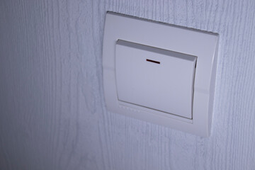 Plastic mechanical white light switch, installed on a light gray wall. High quality photo