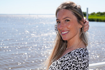 beautiful young blonde woman on the beach coast with hand on hairs