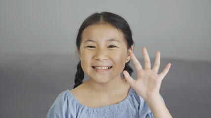 Cute asian little girl smiling and waving hand