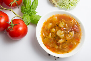 Cabbage and tomato soup with chicken. White background. Next to the ingredients