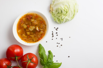 Cabbage and tomato soup with chicken. White background. Next to the ingredients