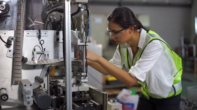 Young female engineer is setting label printer machine in work shop