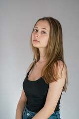 Fototapeta premium Portrait of a languishing and charming young woman with long hair posing looking at the camera on a grey background