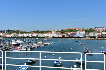 Fishing village and harbour with colorful houses and boats with blue sky. Mugardos, Galicia, Spain. 