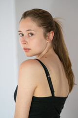 Semi profile portrait of a languishing and charming young woman with ponytail hair posing looking...